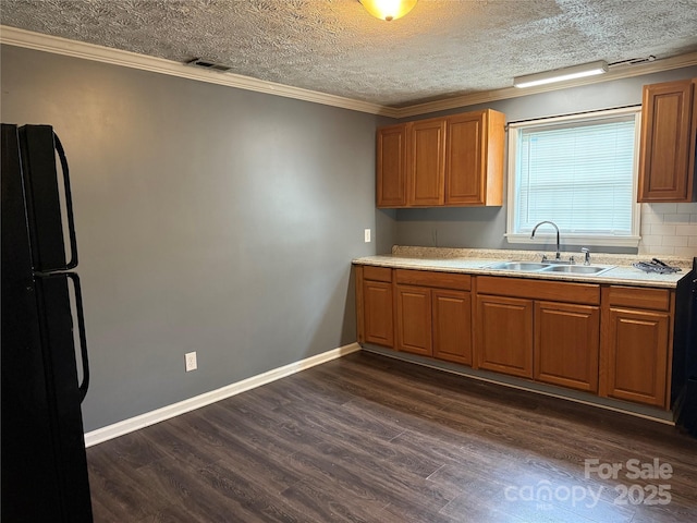 303 Southern Ave, East Spencer, NC 28039 - kitchen with a sink, dark wood-style floors, freestanding refrigerator, brown cabinetry, and ornamental molding