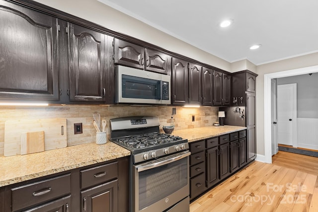 306 Tremont Park Cir SE, Lenoir, NC 28645 - kitchen featuring appliances with stainless steel finishes, light wood finished floors, ornamental molding, dark brown cabinets, and tasteful backsplash