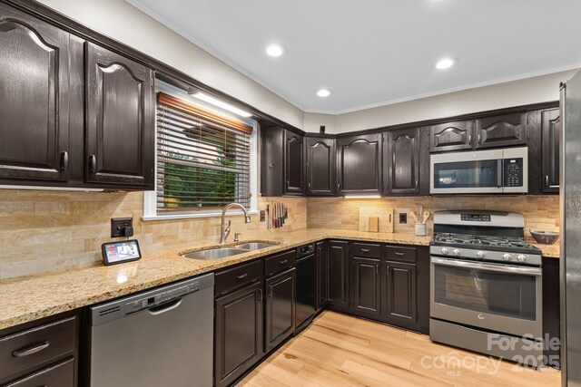 306 Tremont Park Cir SE, Lenoir, NC 28645 - kitchen with stainless steel appliances, a sink, light wood-style flooring, light stone counters, and crown molding