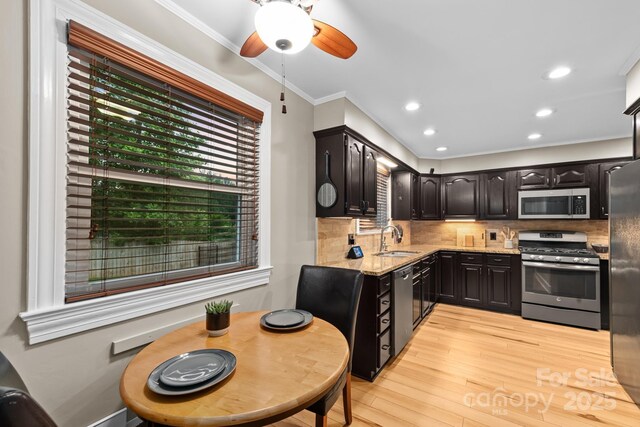 306 Tremont Park Cir SE, Lenoir, NC 28645 - kitchen with appliances with stainless steel finishes, a sink, light wood finished floors, light stone counters, and backsplash