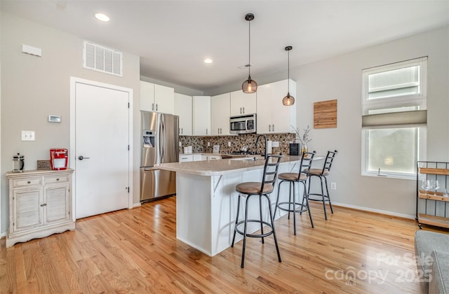 925 Westbrook Dr Unit B, Charlotte, NC 28202 - kitchen with appliances with stainless steel finishes, a peninsula, a breakfast bar, backsplash, and white cabinets