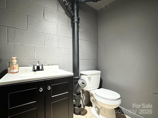 3503 Wyndham Ln, Lenoir, NC 28645 - bathroom featuring toilet, vanity, concrete block wall, and tile patterned floors
