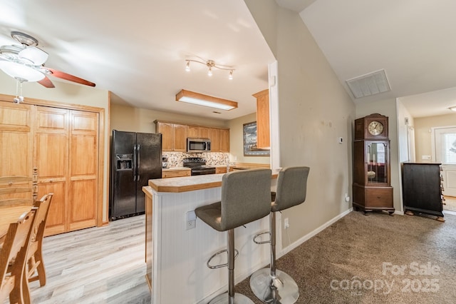 199 Ashmont Dr, Kannapolis, NC 28081 - kitchen with black appliances, light countertops, a peninsula, a breakfast bar area, and a ceiling fan