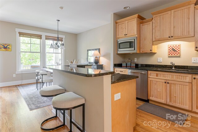 4 Fitzgerald Rd, Black Mountain, NC 28711 - kitchen with stainless steel appliances, a sink, light wood-style floors, light brown cabinets, and a kitchen breakfast bar