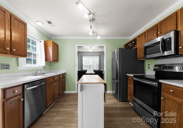 8808 Palmutum Pl, Charlotte, NC 28269 - kitchen featuring appliances with stainless steel finishes, a sink, dark wood-style flooring, a center island, and a textured ceiling