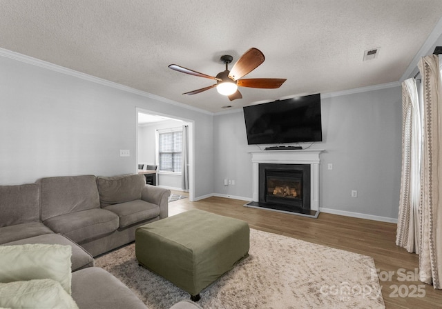8808 Palmutum Pl, Charlotte, NC 28269 - living room with a textured ceiling, a ceiling fan, wood finished floors, crown molding, and a glass covered fireplace