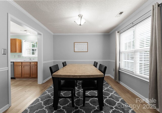 8808 Palmutum Pl, Charlotte, NC 28269 - dining space featuring light wood-style flooring, crown molding, a textured ceiling, and baseboards