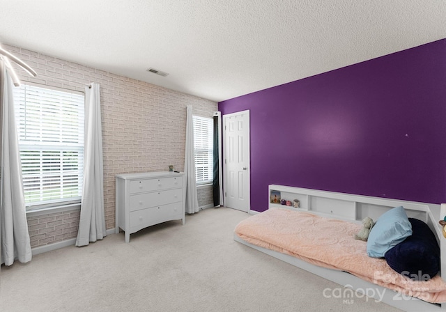 8808 Palmutum Pl, Charlotte, NC 28269 - bedroom with multiple windows, light colored carpet, a textured ceiling, and brick wall