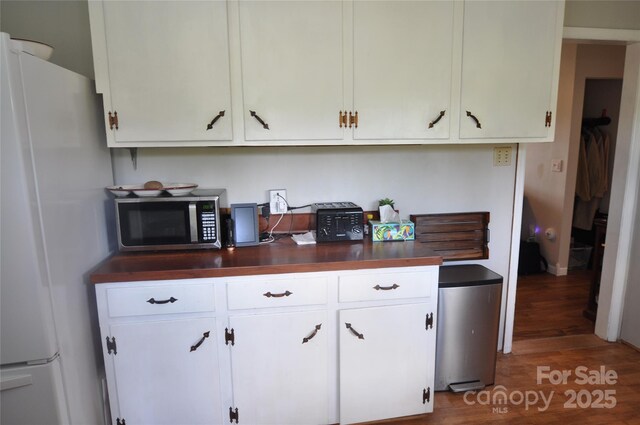 3505 Valley Dr, Chester, SC 29706 - kitchen featuring freestanding refrigerator, stainless steel microwave, wood finished floors, and white cabinetry