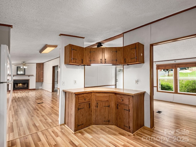 32 Lake Eden Cir, Black Mountain, NC 28711 - kitchen featuring light wood-style flooring, brown cabinets, a textured ceiling, freestanding refrigerator, and a ceiling fan