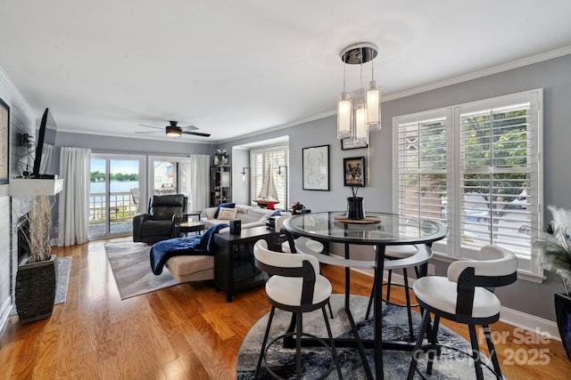 635 Portside Dr, Davidson, NC 28036 - dining space with crown molding, light wood-style floors, ceiling fan, a fireplace, and baseboards