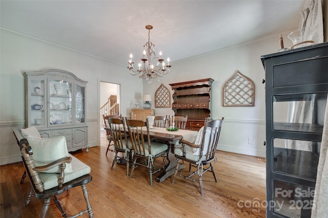 10215 Balmoral Cir, Charlotte, NC 28210 - dining area with a chandelier, ornamental molding, light wood-style floors, and stairway