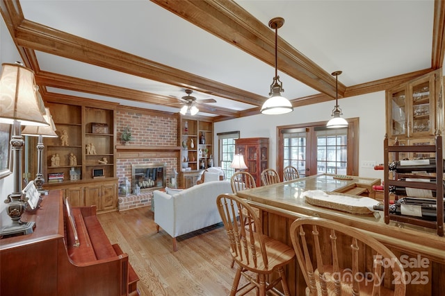 10215 Balmoral Cir, Charlotte, NC 28210 - dining space featuring light wood-style flooring, a brick fireplace, beamed ceiling, and a ceiling fan