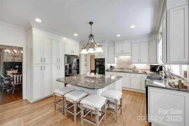 10215 Balmoral Cir, Charlotte, NC 28210 - kitchen featuring black appliances, crown molding, dark stone countertops, decorative backsplash, and light wood-style flooring