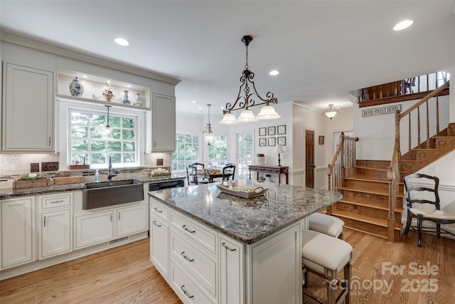 10215 Balmoral Cir, Charlotte, NC 28210 - kitchen with light wood-style floors, a center island, dark stone counters, plenty of natural light, and crown molding