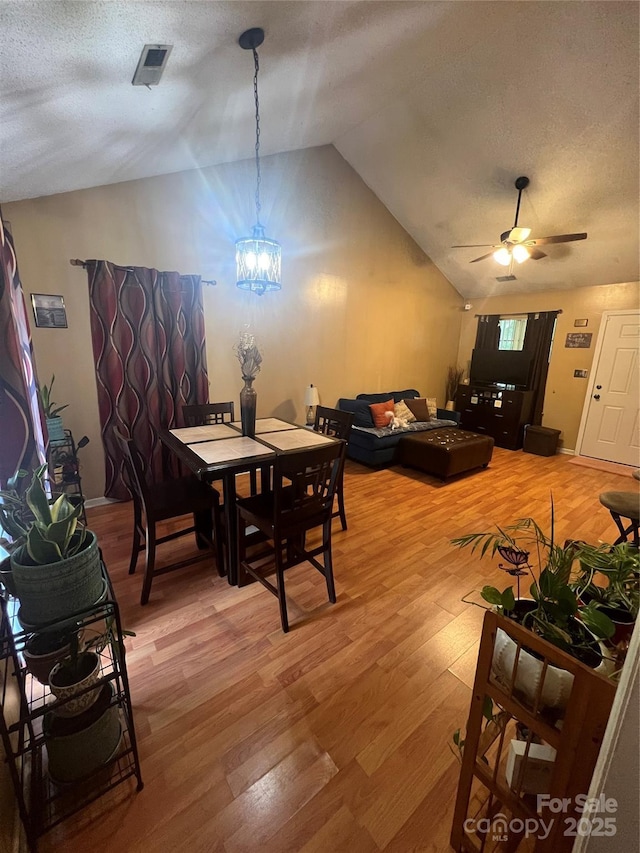 5816 Rocky Mount Ct, Charlotte, NC 28214 - dining area with vaulted ceiling, light wood finished floors, ceiling fan, a chandelier, and a textured ceiling