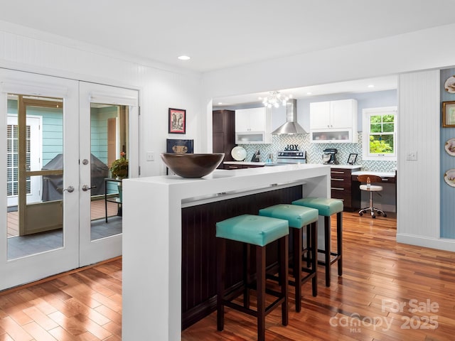 1165 Mountain Laurel Dr, Columbus, NC 28722 - kitchen with wall chimney exhaust hood, a kitchen bar, range, wood finished floors, and light countertops