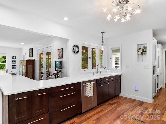 1165 Mountain Laurel Dr, Columbus, NC 28722 - kitchen featuring stainless steel dishwasher, a sink, a peninsula, light wood-style flooring, and light countertops