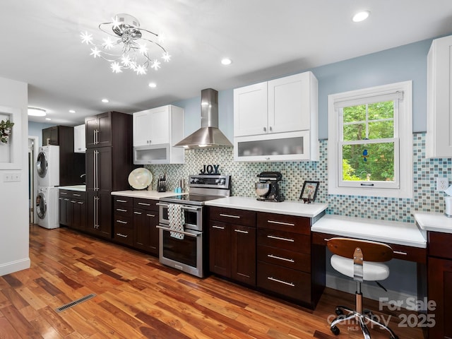 1165 Mountain Laurel Dr, Columbus, NC 28722 - kitchen featuring wall chimney exhaust hood, double oven range, stacked washing machine and dryer, light countertops, and recessed lighting