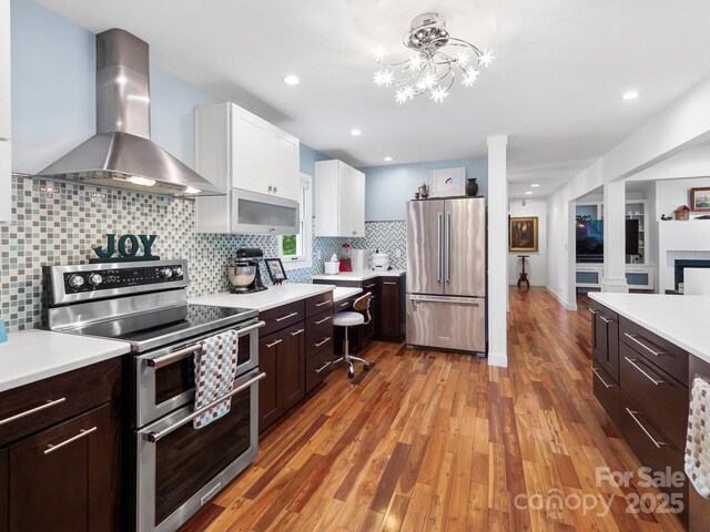 1165 Mountain Laurel Dr, Columbus, NC 28722 - kitchen featuring stainless steel appliances, wall chimney range hood, light countertops, white cabinets, and recessed lighting