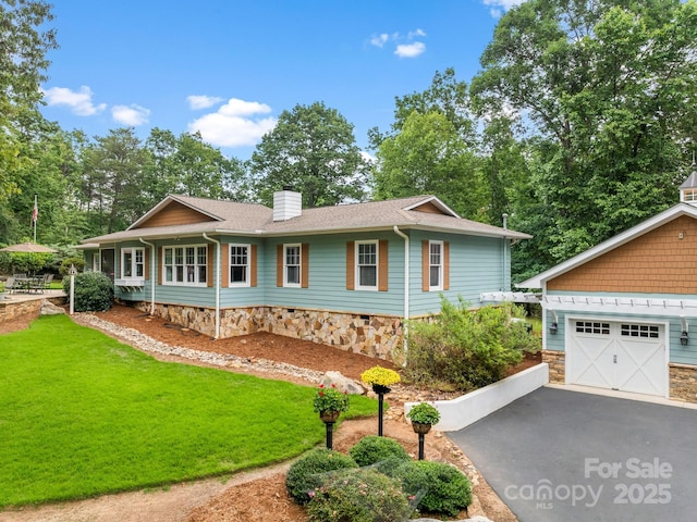 1165 Mountain Laurel Dr, Columbus, NC 28722 - view of front of house featuring a garage, a front yard, driveway, a chimney, and stone siding