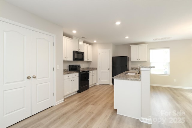 3349 Ellingford Rd, Charlotte, NC 28214 - kitchen featuring black appliances, light wood-style flooring, a sink, white cabinetry, and recessed lighting