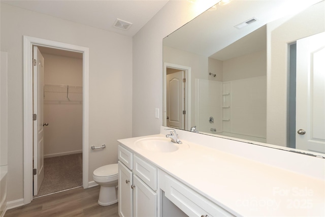 3349 Ellingford Rd, Charlotte, NC 28214 - bathroom with wood finished floors, vanity, toilet, a spacious closet, and baseboards
