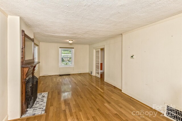 20 Kenilwood Pl, Asheville, NC 28803 - unfurnished living room featuring a textured ceiling, light wood-style flooring, and baseboards