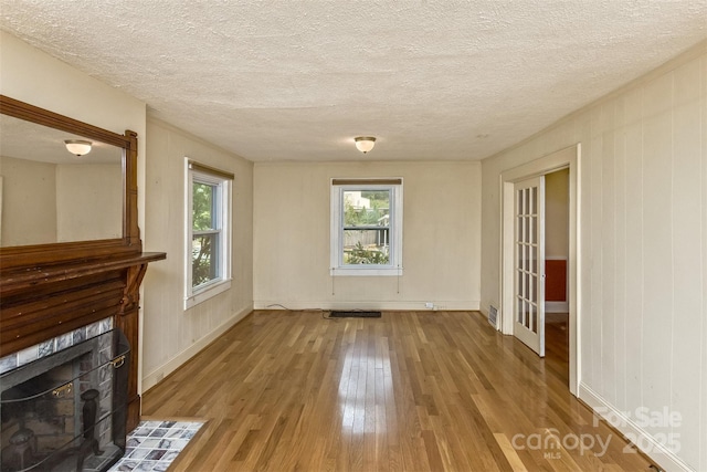 20 Kenilwood Pl, Asheville, NC 28803 - unfurnished living room with wood finished floors, a fireplace, a textured ceiling, and baseboards