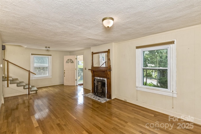 20 Kenilwood Pl, Asheville, NC 28803 - unfurnished living room with stairs, a textured ceiling, wood finished floors, a fireplace with flush hearth, and baseboards