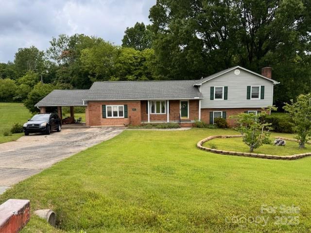 6561 Weldon Cir NW, Concord, NC 28027 - tri-level home featuring driveway, brick siding, a front lawn, an attached carport, and a chimney