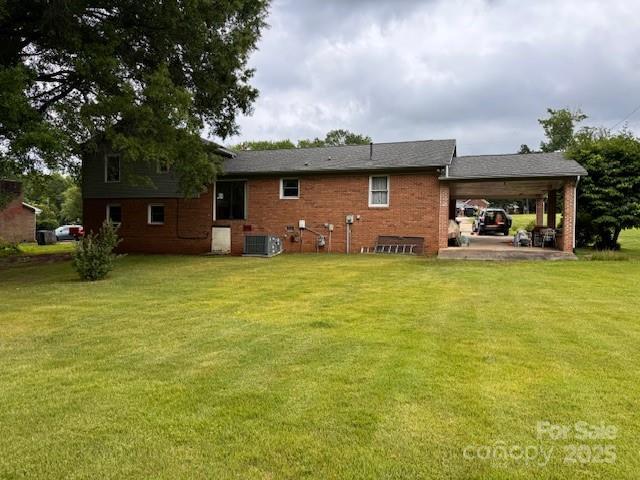 6561 Weldon Cir NW, Concord, NC 28027 - rear view of property with a yard, central air condition unit, an attached carport, and brick siding