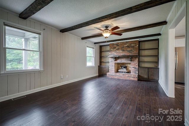 2653 Fairway Acres Cir, Lenoir, NC 28645 - unfurnished living room featuring a textured ceiling, dark wood-type flooring, beamed ceiling, a brick fireplace, and a ceiling fan