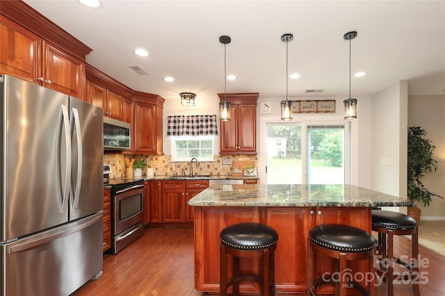 2018 Rosewater Ln, Indian Trail, NC 28079 - kitchen featuring stainless steel appliances, a sink, decorative backsplash, dark wood-style flooring, and a kitchen breakfast bar