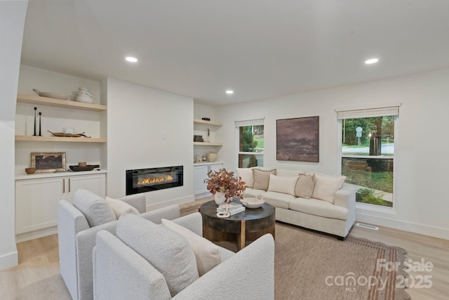 3326 Winterfield Pl, Charlotte, NC 28205 - living area with light wood-style flooring, a glass covered fireplace, recessed lighting, baseboards, and built in shelves