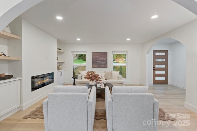 3326 Winterfield Pl, Charlotte, NC 28205 - living room with arched walkways, light wood-style flooring, a glass covered fireplace, recessed lighting, and baseboards