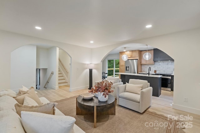 3326 Winterfield Pl, Charlotte, NC 28205 - living room featuring arched walkways, light wood-style flooring, stairs, recessed lighting, and baseboards
