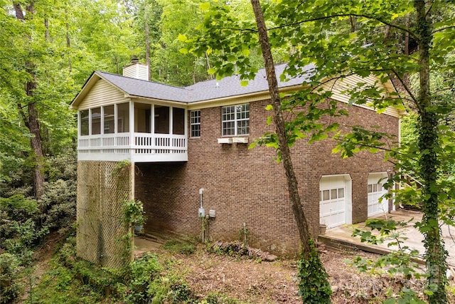 608 Surrey Glen Cir, Hendersonville, NC 28739 - rear view of house featuring a sunroom, driveway, a chimney, a garage, and brick siding
