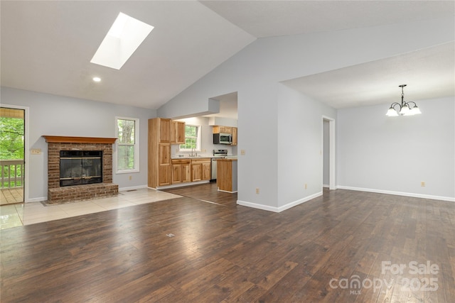 608 Surrey Glen Cir, Hendersonville, NC 28739 - unfurnished living room featuring hardwood / wood-style floors, healthy amount of natural light, a fireplace, a skylight, and high vaulted ceiling