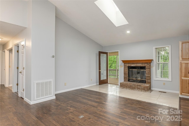 608 Surrey Glen Cir, Hendersonville, NC 28739 - unfurnished living room with wood finished floors, high vaulted ceiling, a fireplace, a skylight, and baseboards