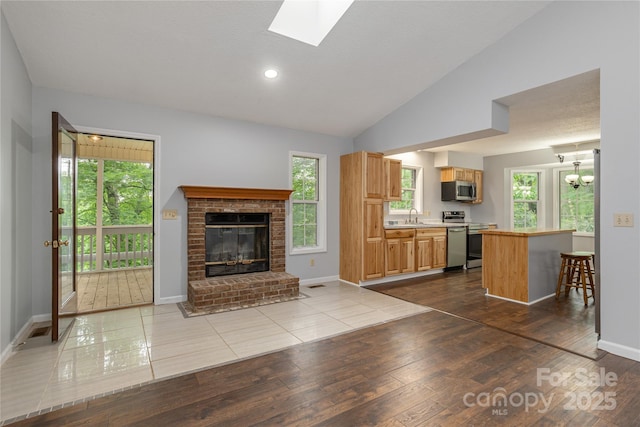 608 Surrey Glen Cir, Hendersonville, NC 28739 - kitchen featuring stainless steel appliances, a sink, light countertops, a fireplace, and lofted ceiling