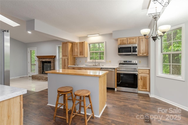 608 Surrey Glen Cir, Hendersonville, NC 28739 - kitchen with appliances with stainless steel finishes, light brown cabinets, dark wood-type flooring, a chandelier, and a textured ceiling