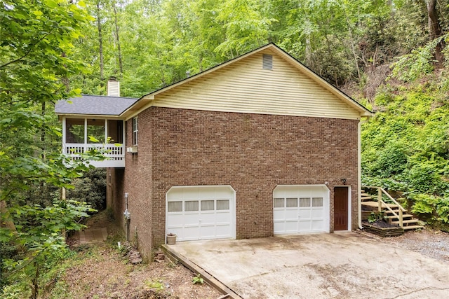608 Surrey Glen Cir, Hendersonville, NC 28739 - view of property exterior with an attached garage, a chimney, concrete driveway, brick siding, and a sunroom