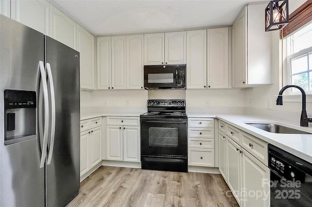 720 Reigate Rd, Charlotte, NC 28262 - kitchen with black appliances, light wood-type flooring, and white cabinetry