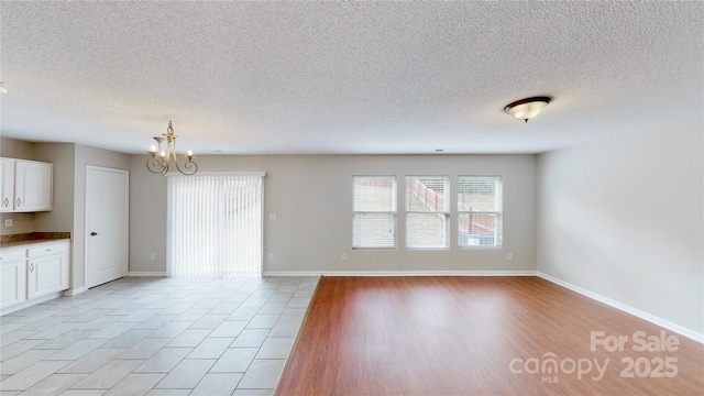 8139 Deodora Cedar Ln, Charlotte, NC 28215 - unfurnished living room featuring healthy amount of natural light, a chandelier, a textured ceiling, and baseboards