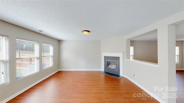 8139 Deodora Cedar Ln, Charlotte, NC 28215 - unfurnished living room with wood finished floors, a textured ceiling, a fireplace with flush hearth, and baseboards