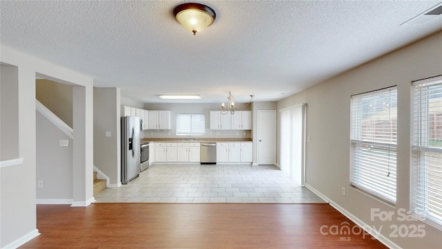 8139 Deodora Cedar Ln, Charlotte, NC 28215 - kitchen featuring stainless steel appliances, white cabinets, light countertops, a sink, and light wood-type flooring