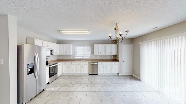 8139 Deodora Cedar Ln, Charlotte, NC 28215 - kitchen featuring appliances with stainless steel finishes, a sink, light countertops, white cabinets, and a chandelier