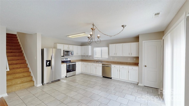 8139 Deodora Cedar Ln, Charlotte, NC 28215 - kitchen featuring appliances with stainless steel finishes, a sink, light countertops, a chandelier, and white cabinetry