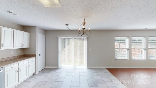 8139 Deodora Cedar Ln, Charlotte, NC 28215 - unfurnished dining area featuring a chandelier, a textured ceiling, light tile patterned floors, and baseboards